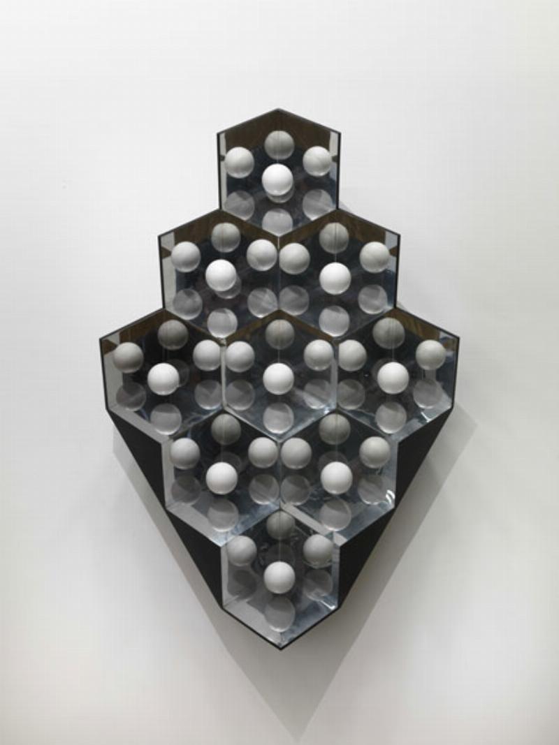 Une grande sculpture cinétique contemporaine et interactive, avec des jeux de lumière et des formes abstraites, invitant le public à participer à son mouvement.